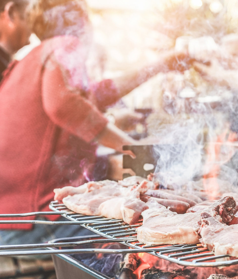 Bone-in pork chops and sausages cooking over a charcoal grill