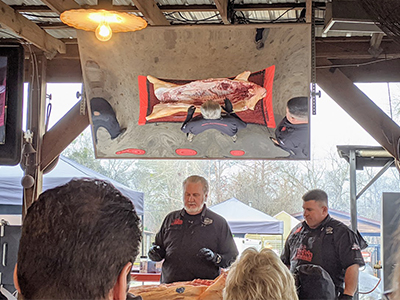 Myron Mixon walks the class through hog anatomy using the whole carcass