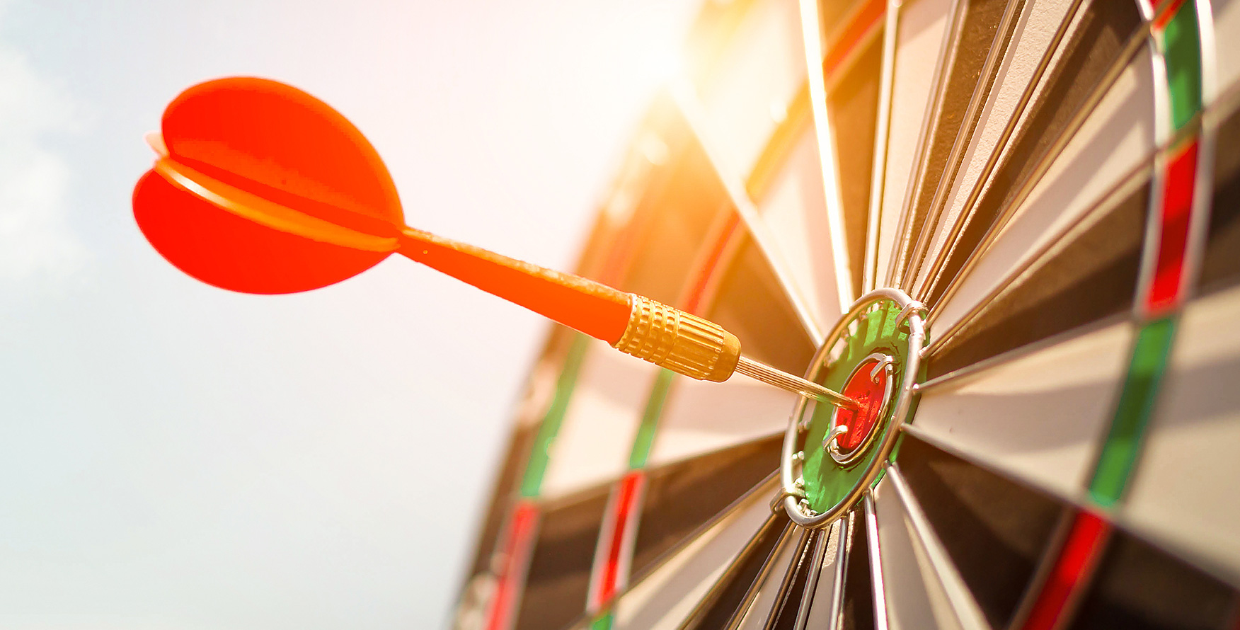 Dart arrow hitting a target in the center of a dartboard.