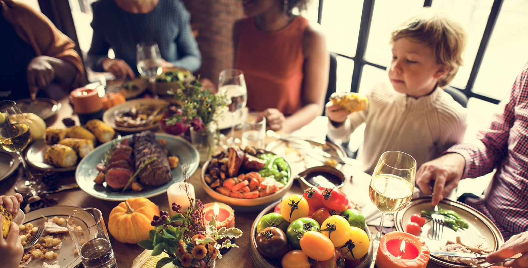 A family meal happening around a table  full of food 