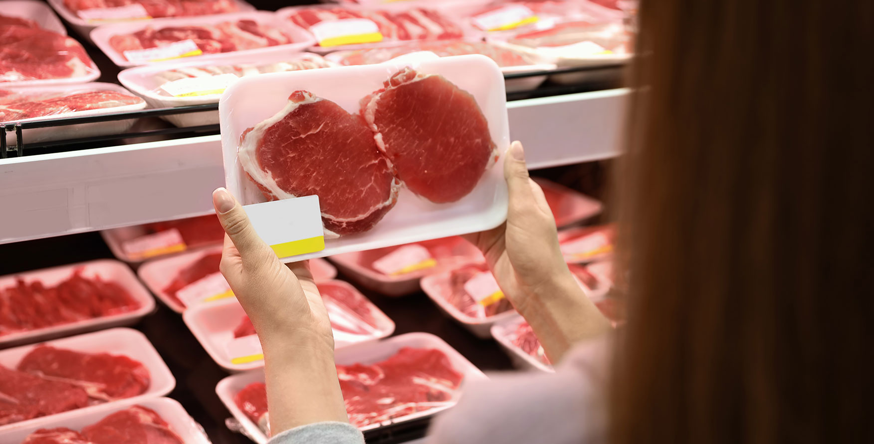 A consumer holding up packaged pork chops in the grocery store
