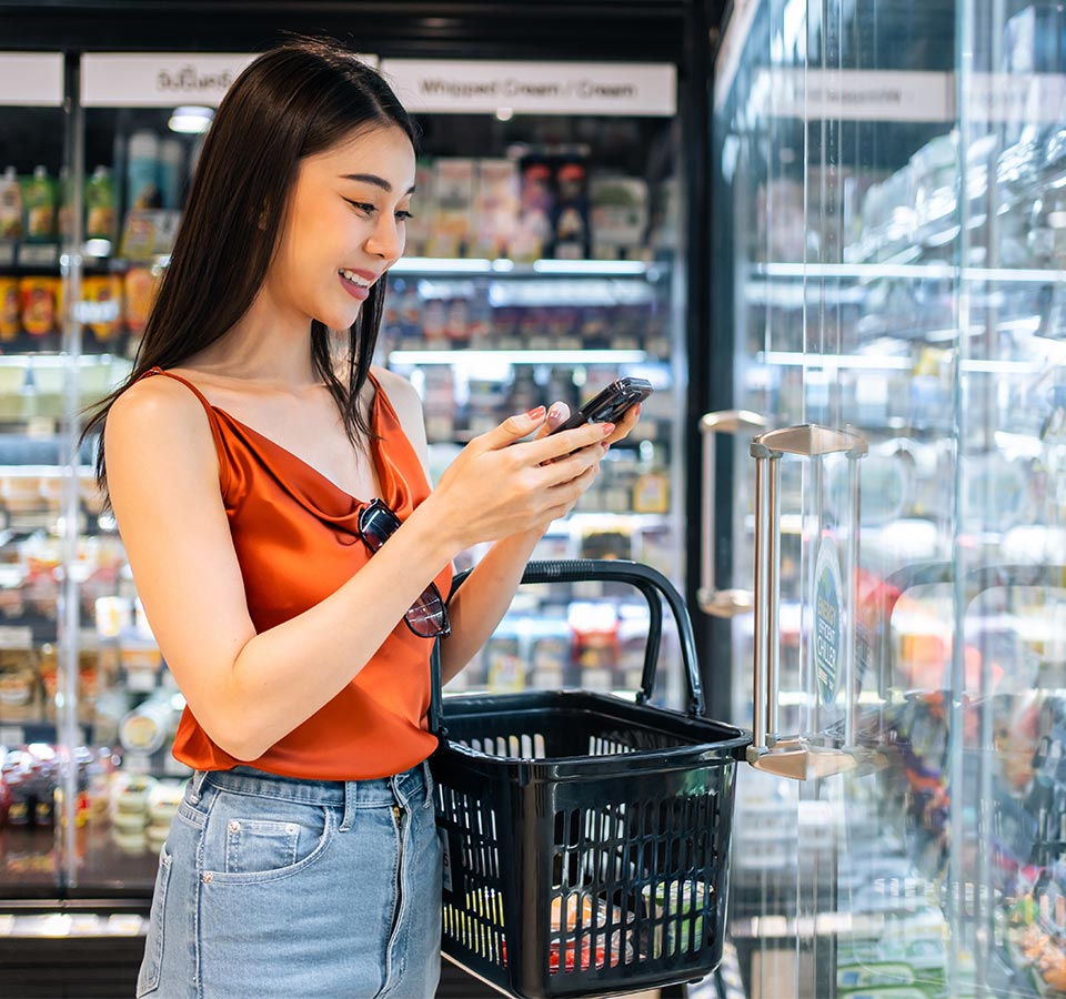 A GenZ shopper looks at her phone in the grocery aisle