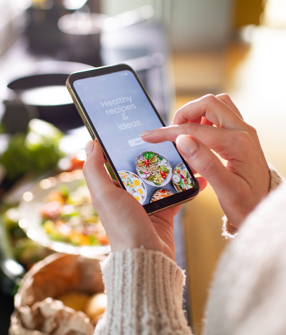 Hand scrolling through recipes ideas on a mobile phone in a store