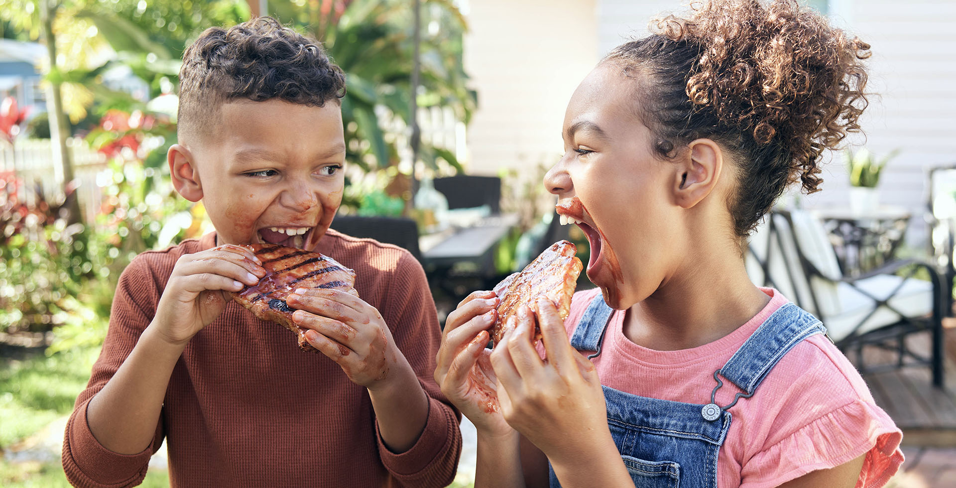 Two kids eating ribs and getting messy