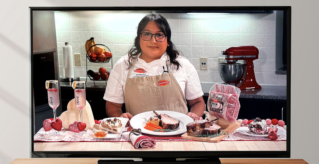 A chef on a computer monitor standing in front of a plated meal
