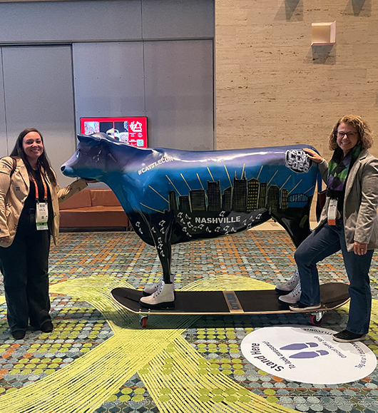 Midan teammates standing beside a statue of a cow wearing shoes standing on a skateboard